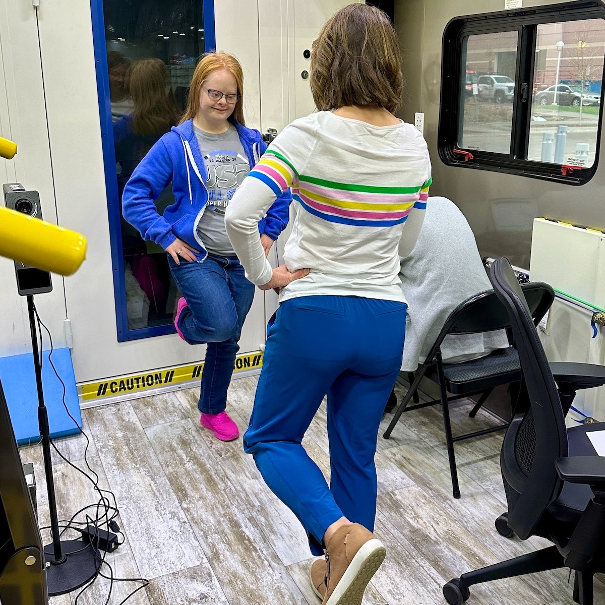 Young woman with Down syndrome balancing on one foot with a researcher