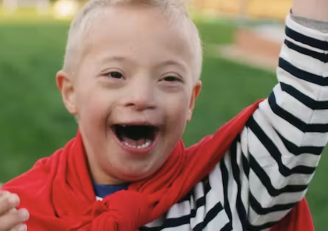 Image of boy with Down syndrome wearing a super hero cape