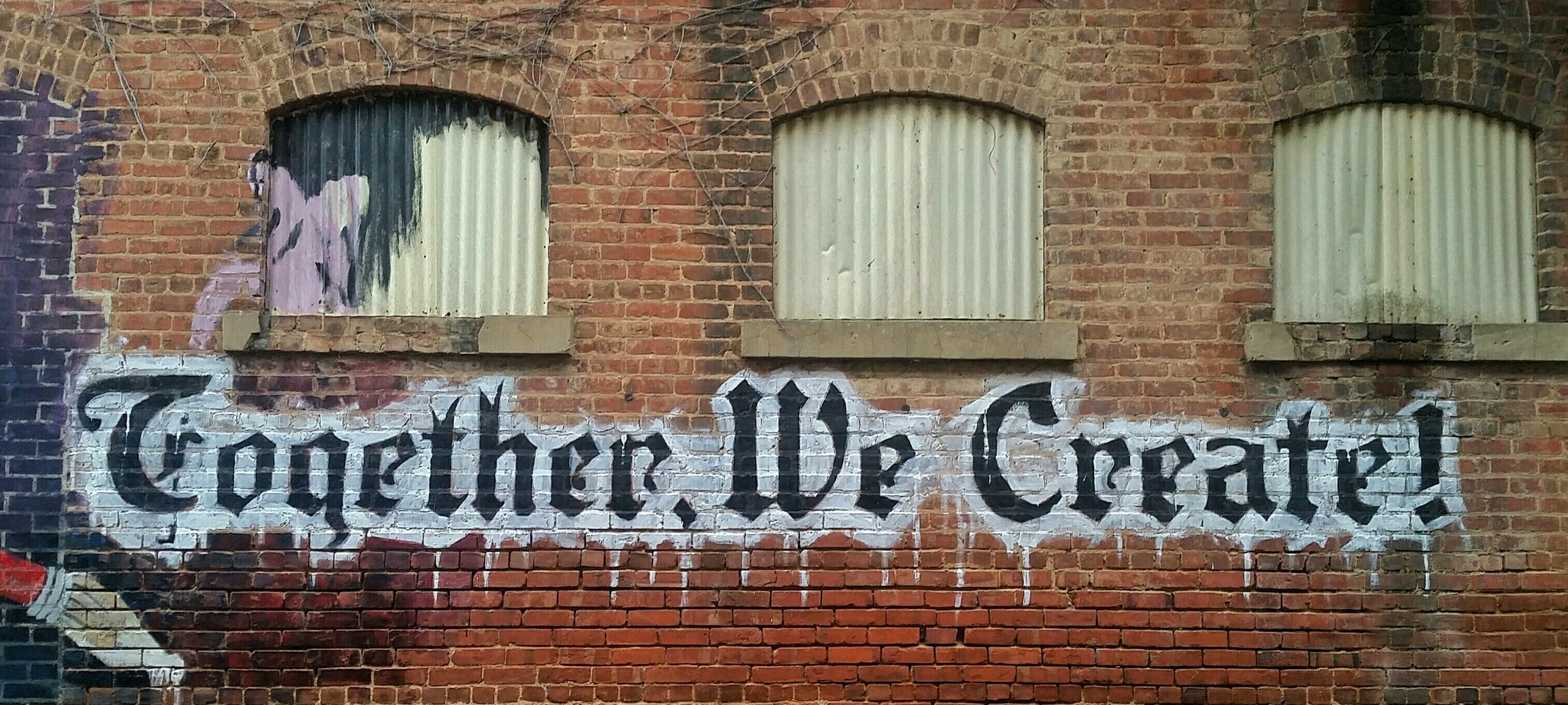 Together we create spraypainted on brick wall of old building