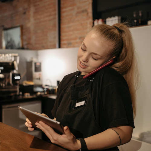 White teenage girl working as a cashier on the phone