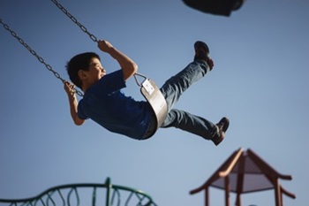 Boy swinging on a park swing set
